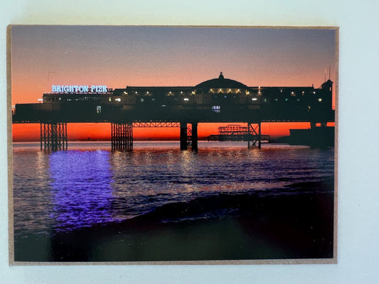 Brighton Pier and The west Pier at sunset with an orange glow. Greeting card